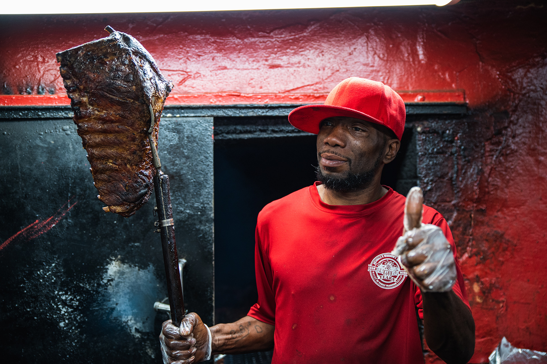 Deondre Richardson poses with a hickory smoked rack of ribs held with a homemade turning fork attached to a hoe handle.