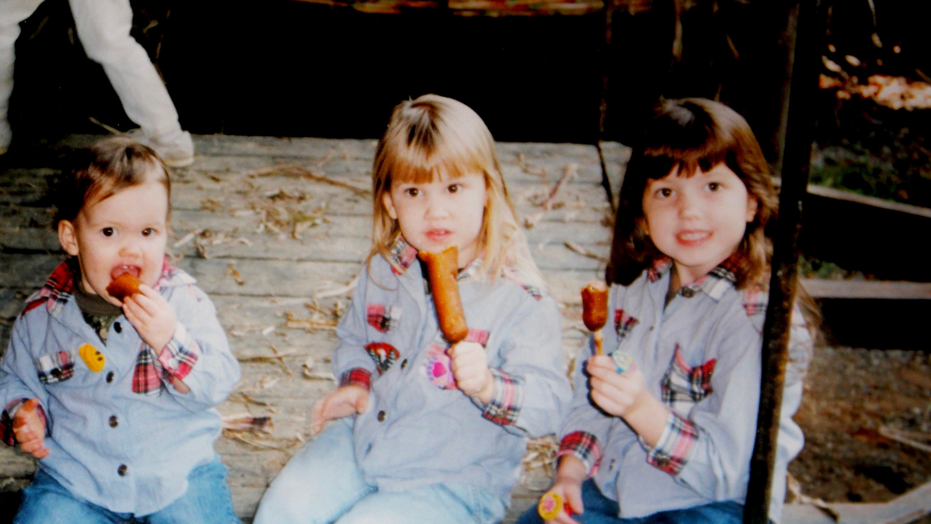 In a 2001 snapshot, the author and her sisters, Kelci and Ashton, chow down on corn dogs at the Blairsville Sorghum Festival.
