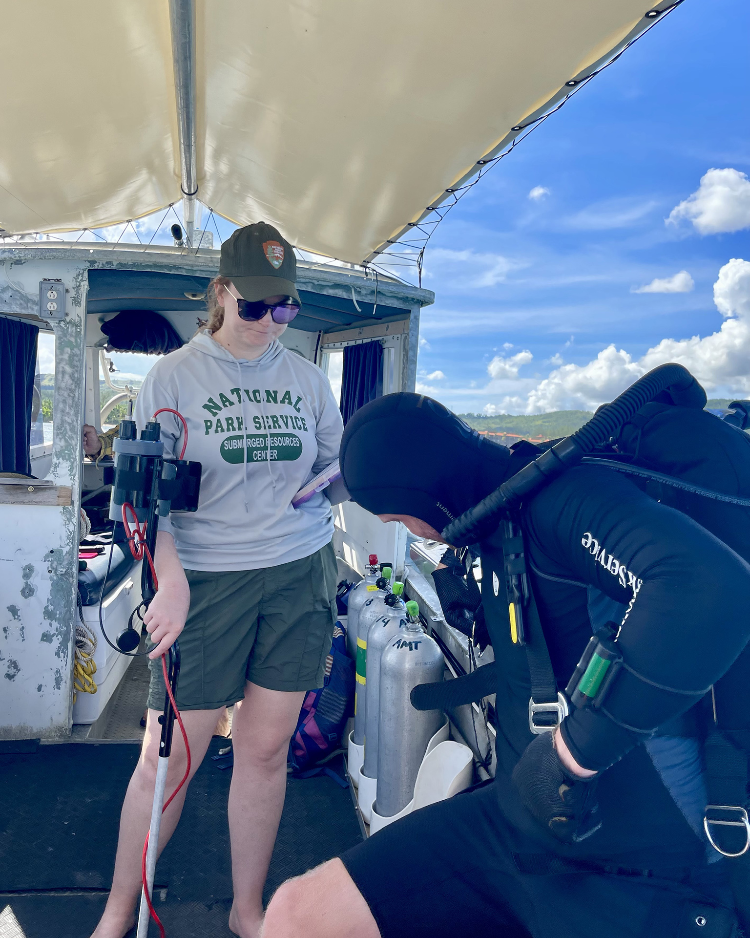 On a dive boat off Guam,  National Park Service Submerged Resources Center team leader and underwater archaeologist Annie Nunn helps fellow archaeologist Matt Hanks prepare to dive (photograph by Russell Worth Parker).